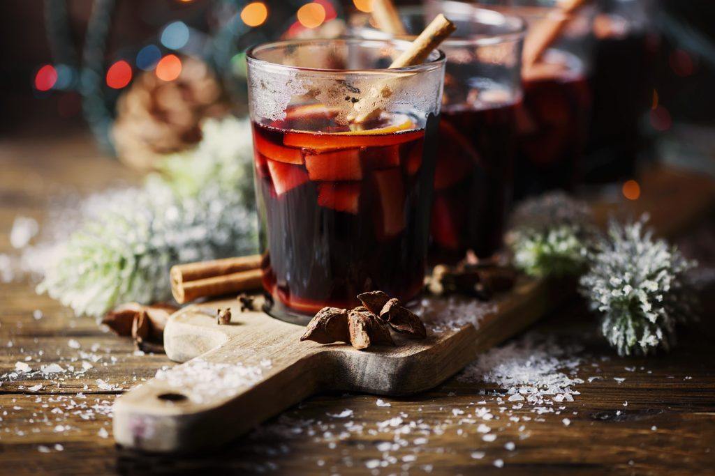 a mug of glühwein utop a chopping board, surrounded by seasonal decorations