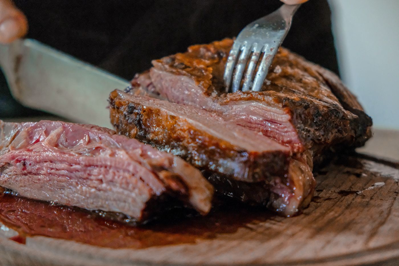 Pairing wine with beef - someone tucking into a juicy piece of meat